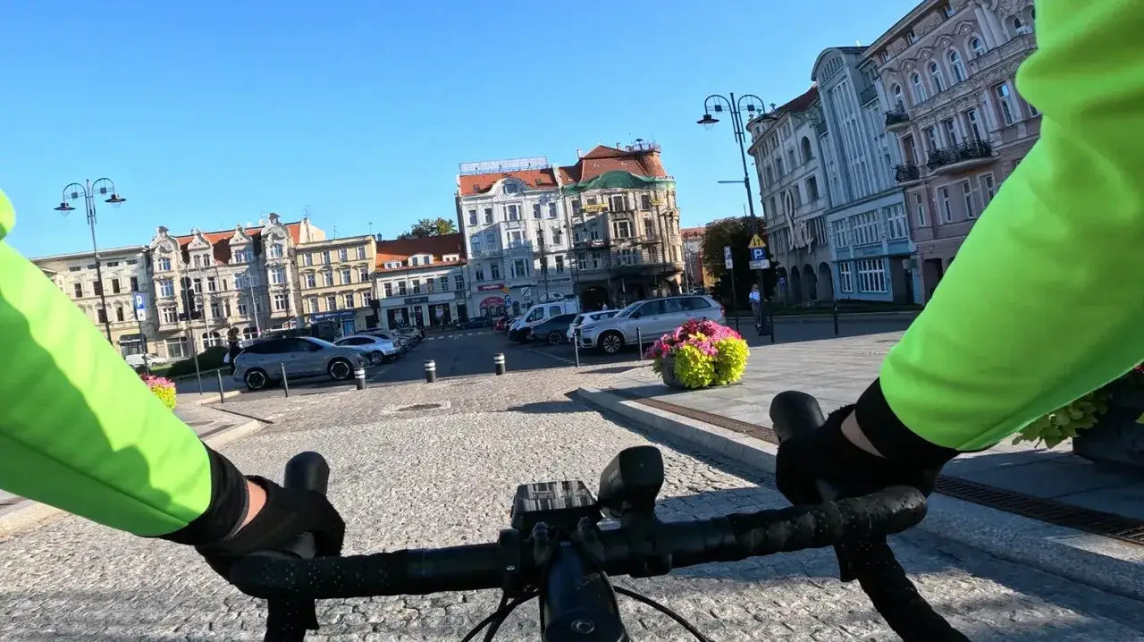 Rowerem do pracy przez urokliwy rynek. Słoneczny dzień, zabytkowe kamienice i kwitnące kwiaty.