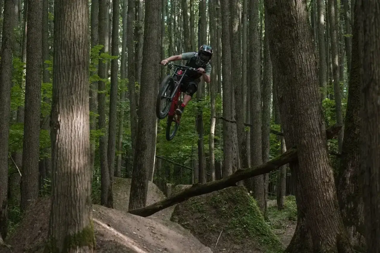 Kolarz MTB w powietrzu na leśnych trasach.