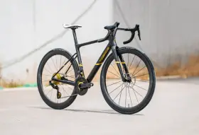 Czarny rower szosowy z żółtymi akcentami. To jeden z nowoczesnych rodzajów ram rowerowych, wykonany z włókna węglowego.