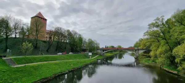 Oświęcim trasa: zamek, rzeka Soła i most na tle pochmurnego nieba.