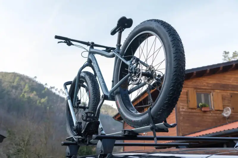 Gotowy montaż bagażnika rowerowego na dachu samochodu. Grube opony roweru fat bike są gotowe na przygodę.